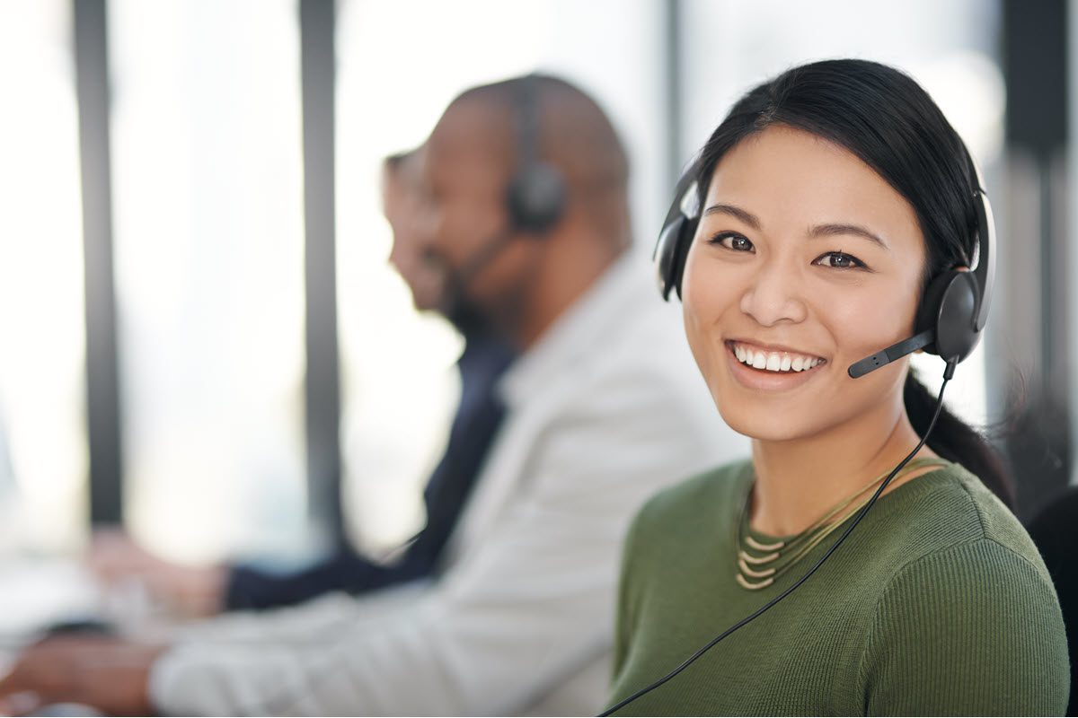 Call Center with Asian Woman Smiling in Foreground 1200x800