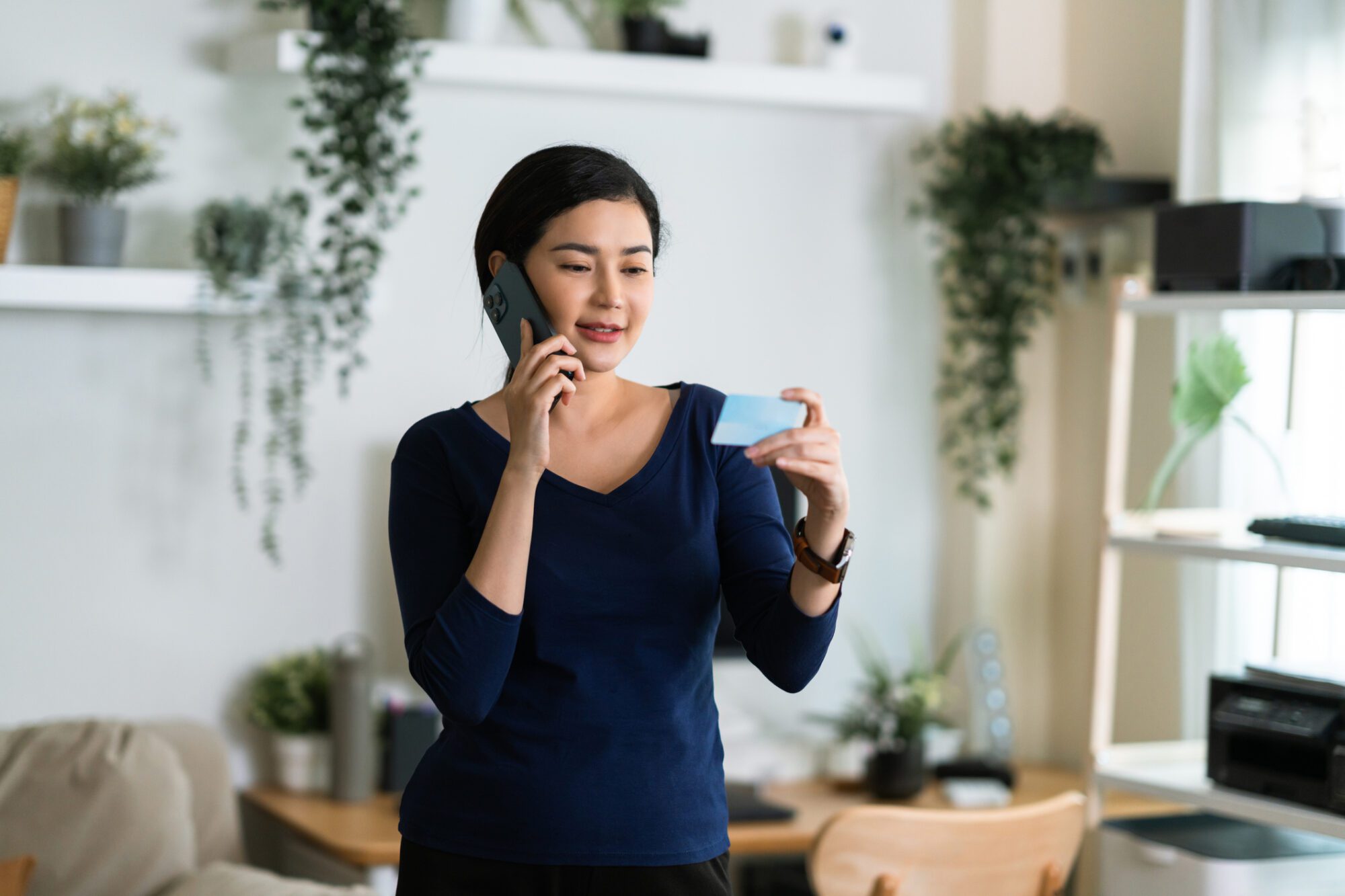 Asian woman on phone holding a card